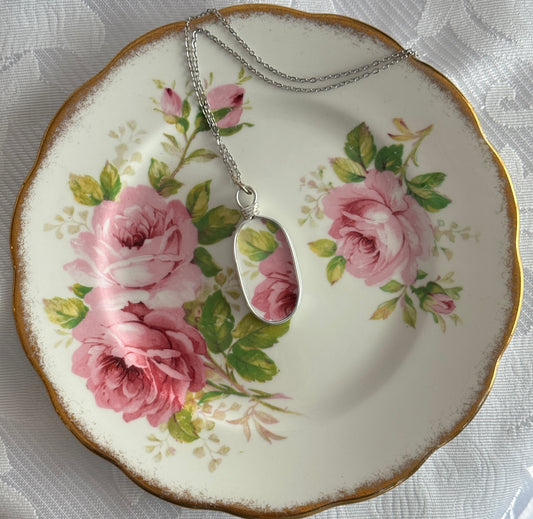 Necklace with a pendant on a decorative plate featuring pink roses.