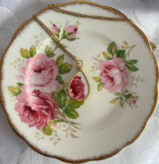 Necklace with a teardrop pendant on a decorative plate with floral design