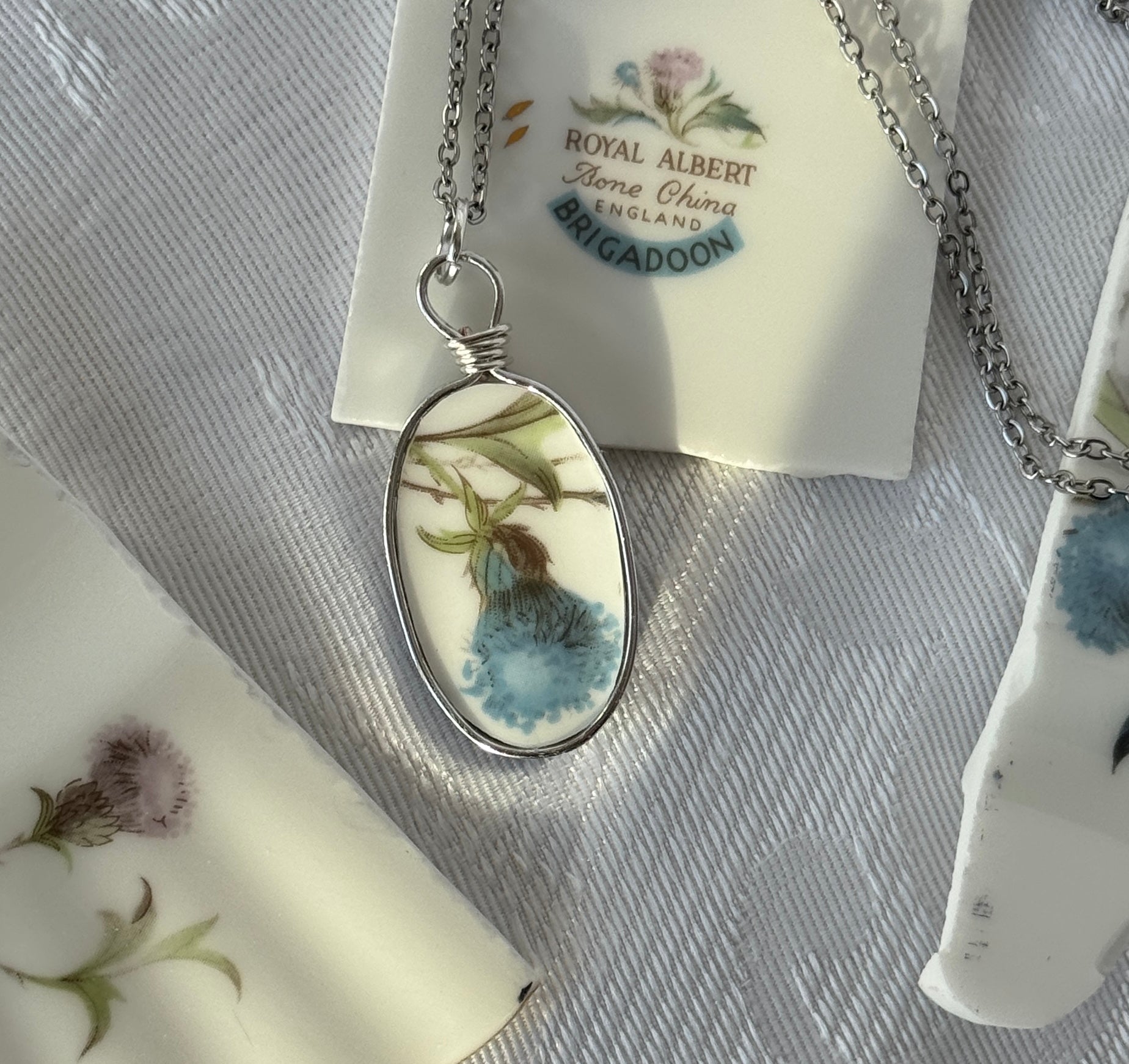 Necklace with a pendant featuring floral design on a Royal Albert tag.