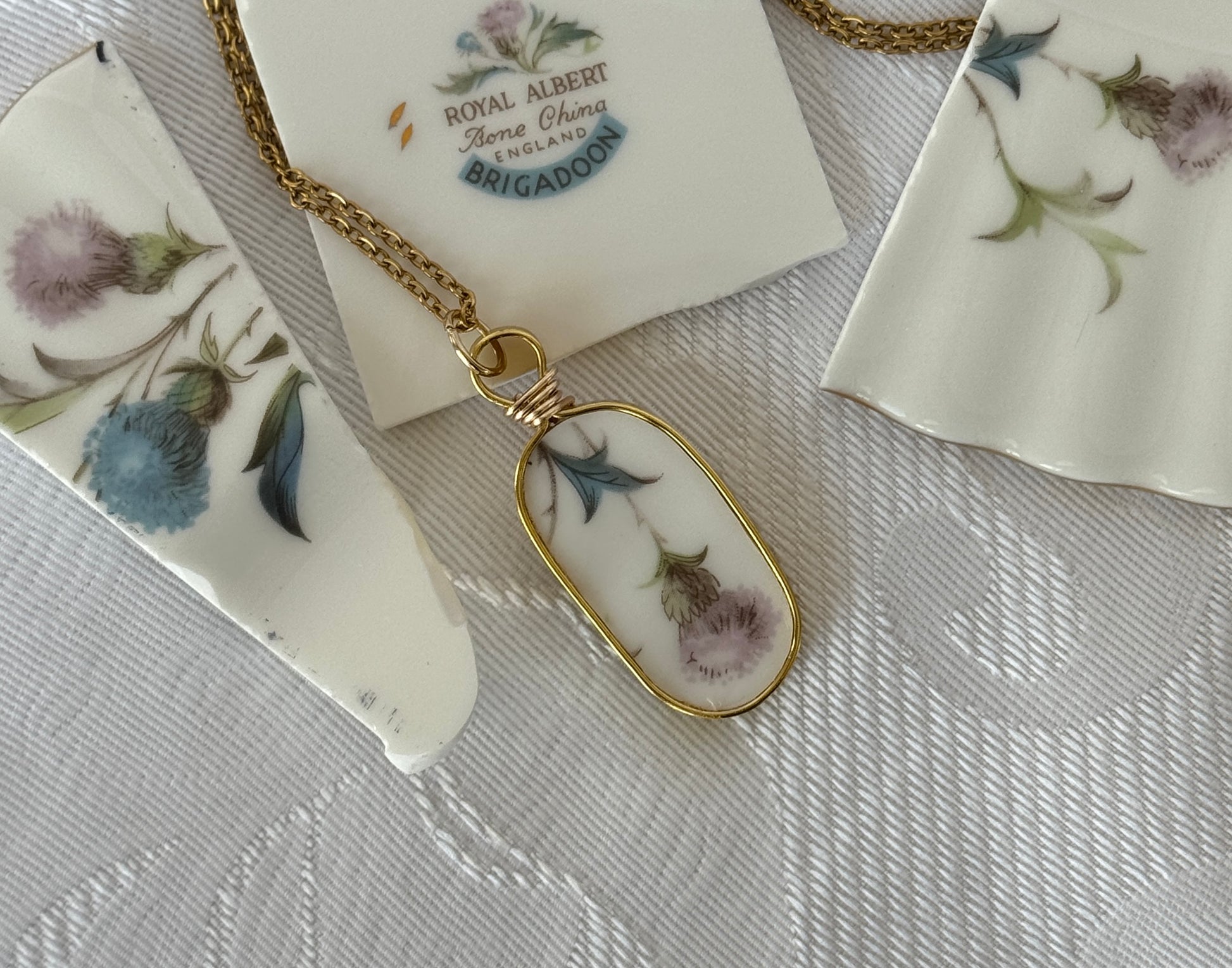 Necklace with a floral pendant on a textured surface with a 'Royal Albert' tag.