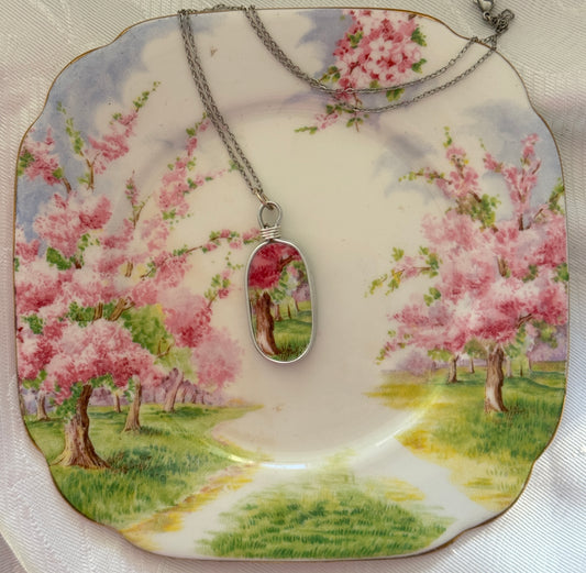 Necklace with a pendant on a decorative plate with cherry blossom design