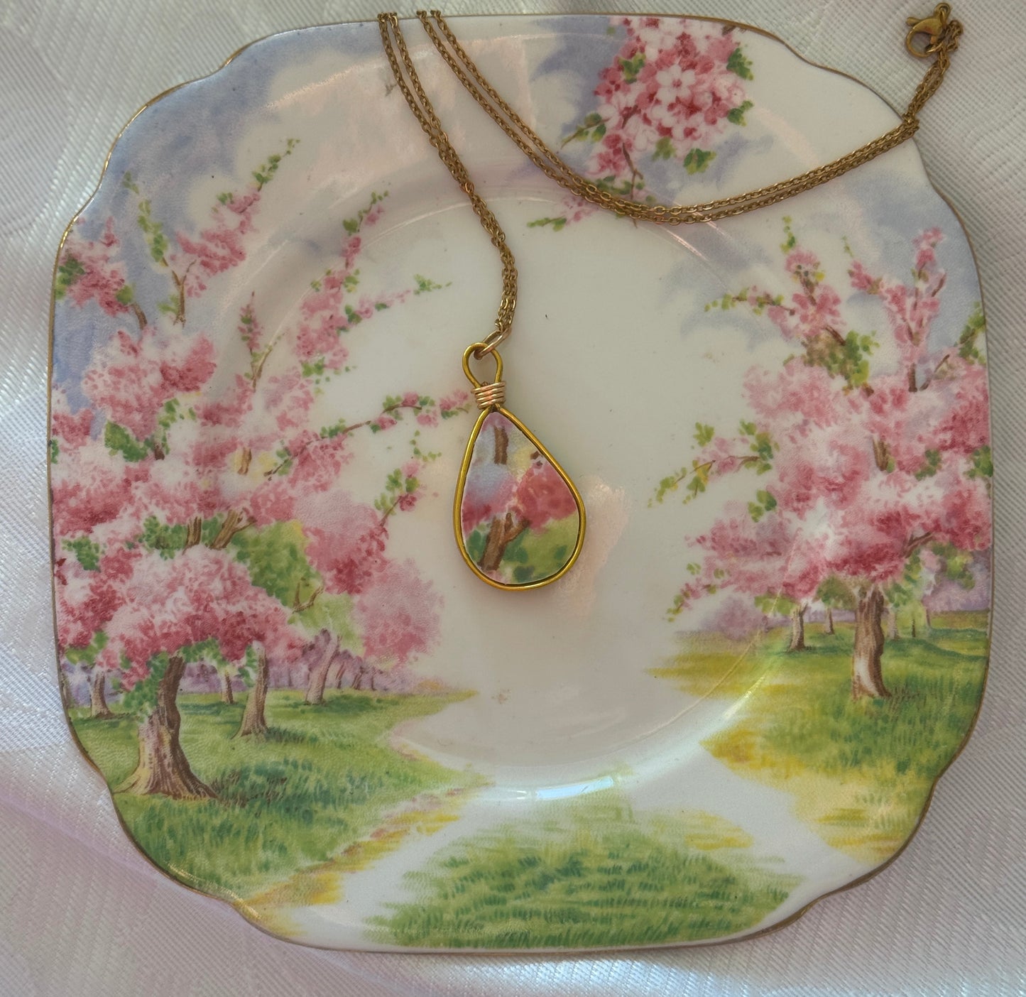 Necklace with a pendant on a decorative plate with cherry blossom design