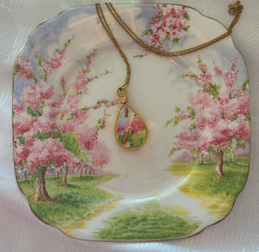 Necklace with a pendant on a decorative plate with cherry blossom design