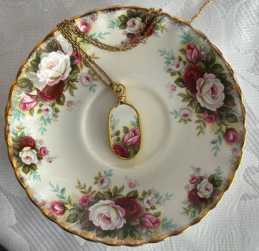 Decorative plate with floral design featuring a pendant on a matching chain.