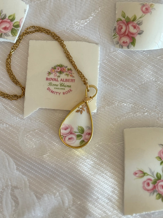 Teardrop-shaped pendant with floral design on a white fabric background, featuring Royal Albert branding.
