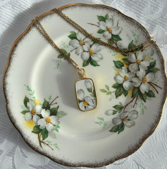 Necklace with a Dogwod floral pendant on a decorative plate with floral patterns