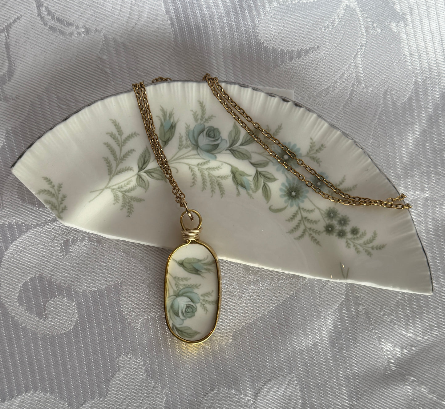 Necklace with a pendant on a decorative plate with floral patterns