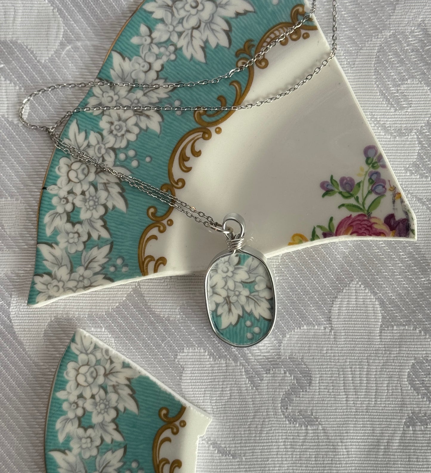 Silver necklace with a floral pendant on a decorative plate