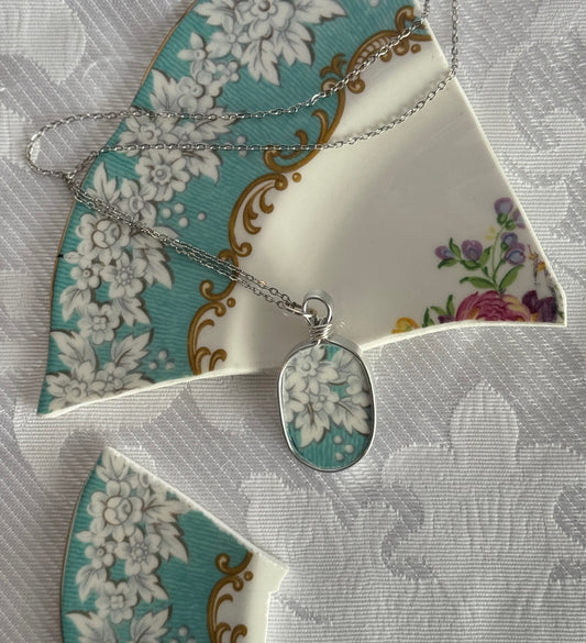 Silver necklace with a floral pendant on a decorative plate