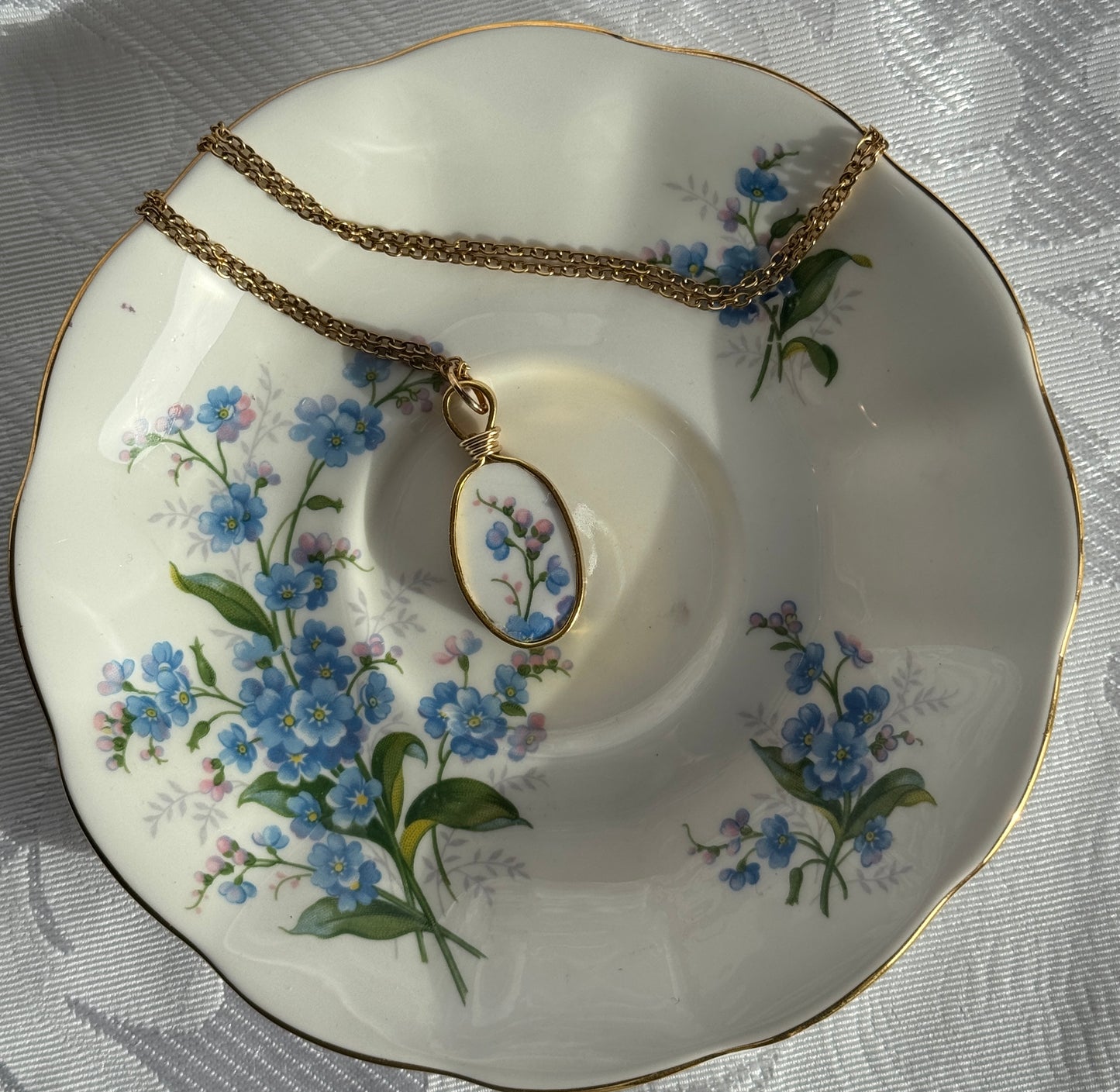 Necklace with a floral pendant on a decorative plate with floral patterns