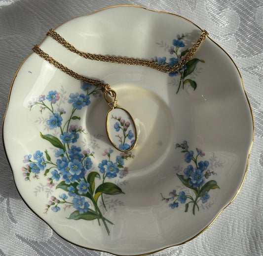 Necklace with a floral pendant on a decorative plate with floral patterns