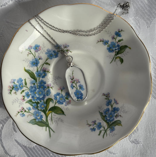 Necklace with a floral pendant on a decorative plate with floral patterns