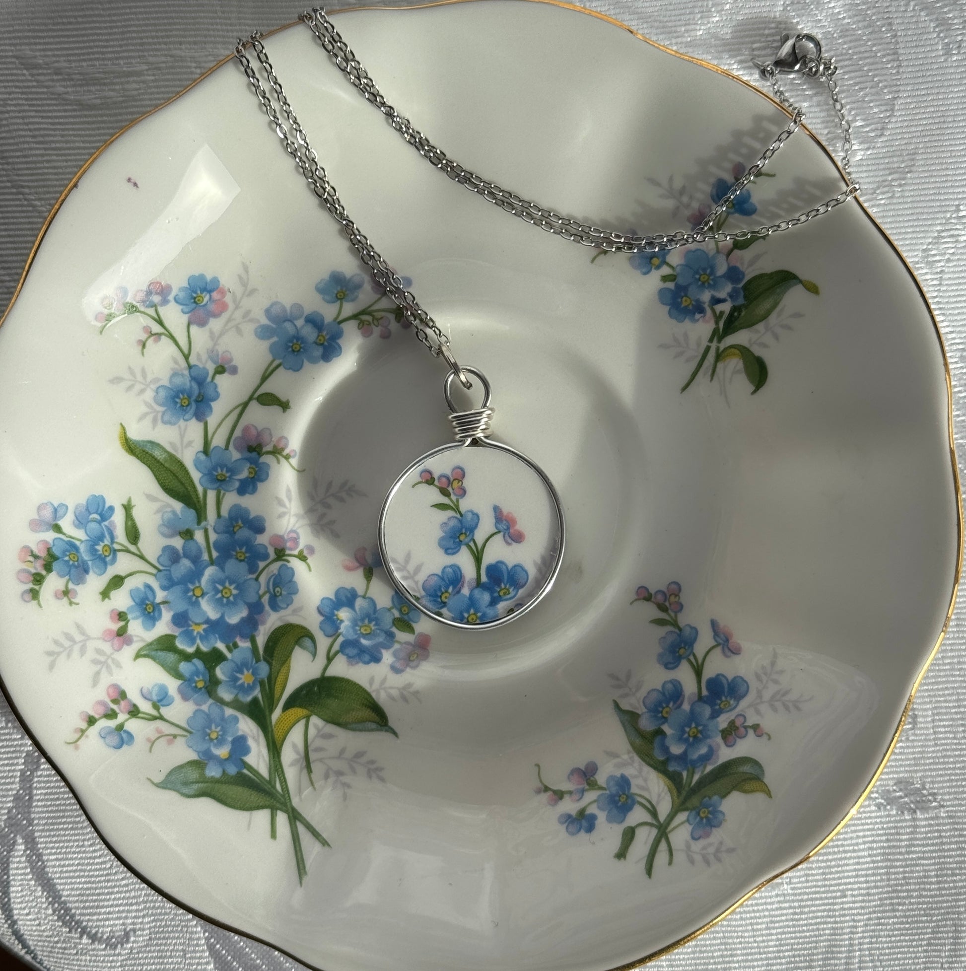 Necklace with floral pendant on a decorative plate with floral design