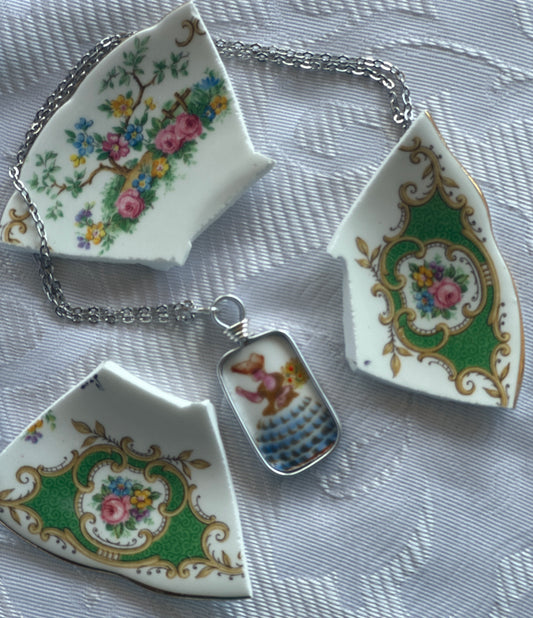 Three decorative ceramic with floral and floral patterns on a chain on a pendant with a lady in a bonnet against a textured background.