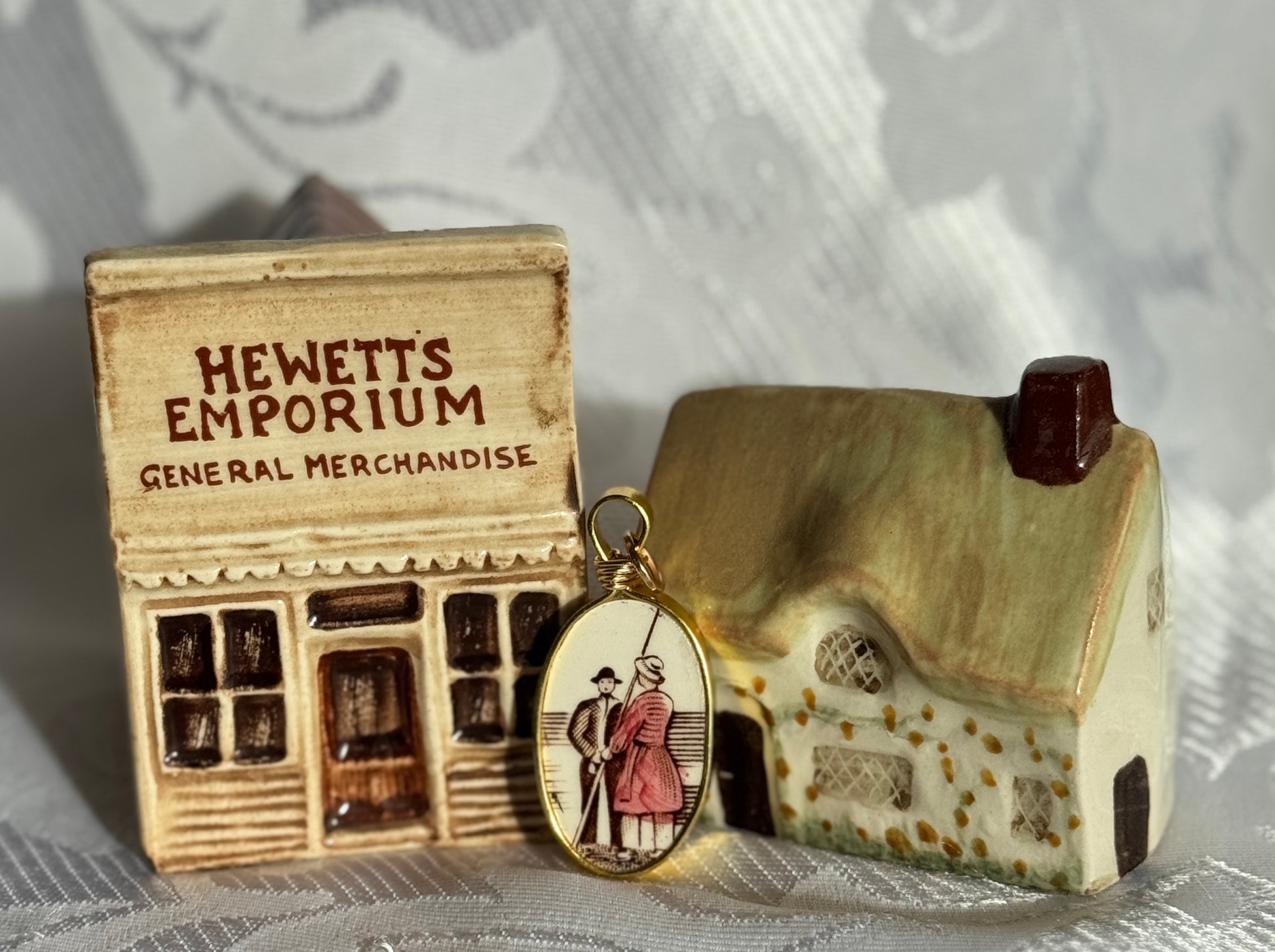 Miniature store model labeled 'Hewett's Emporium' with a pendant featuring a couple and a house.