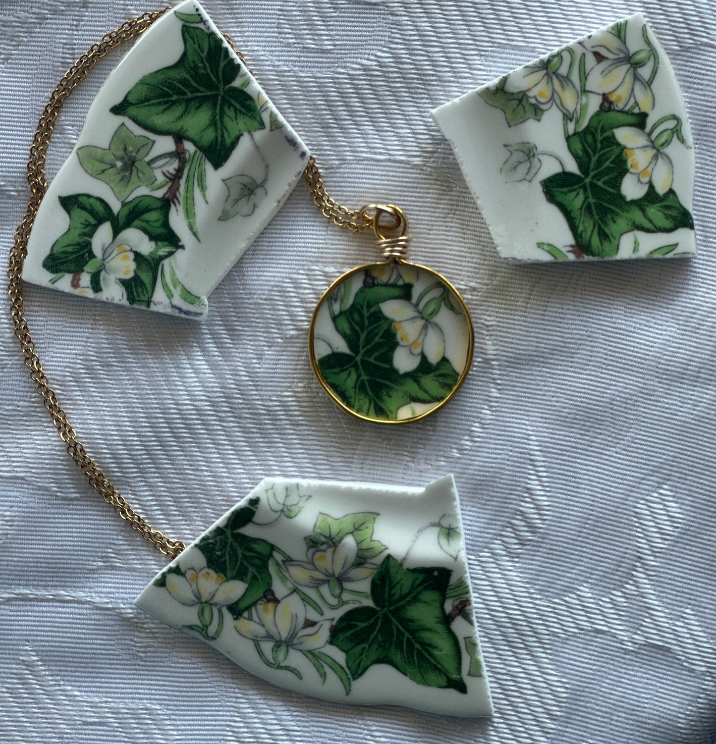 Necklace with floral pendant and matching ceramic pieces on a textured surface