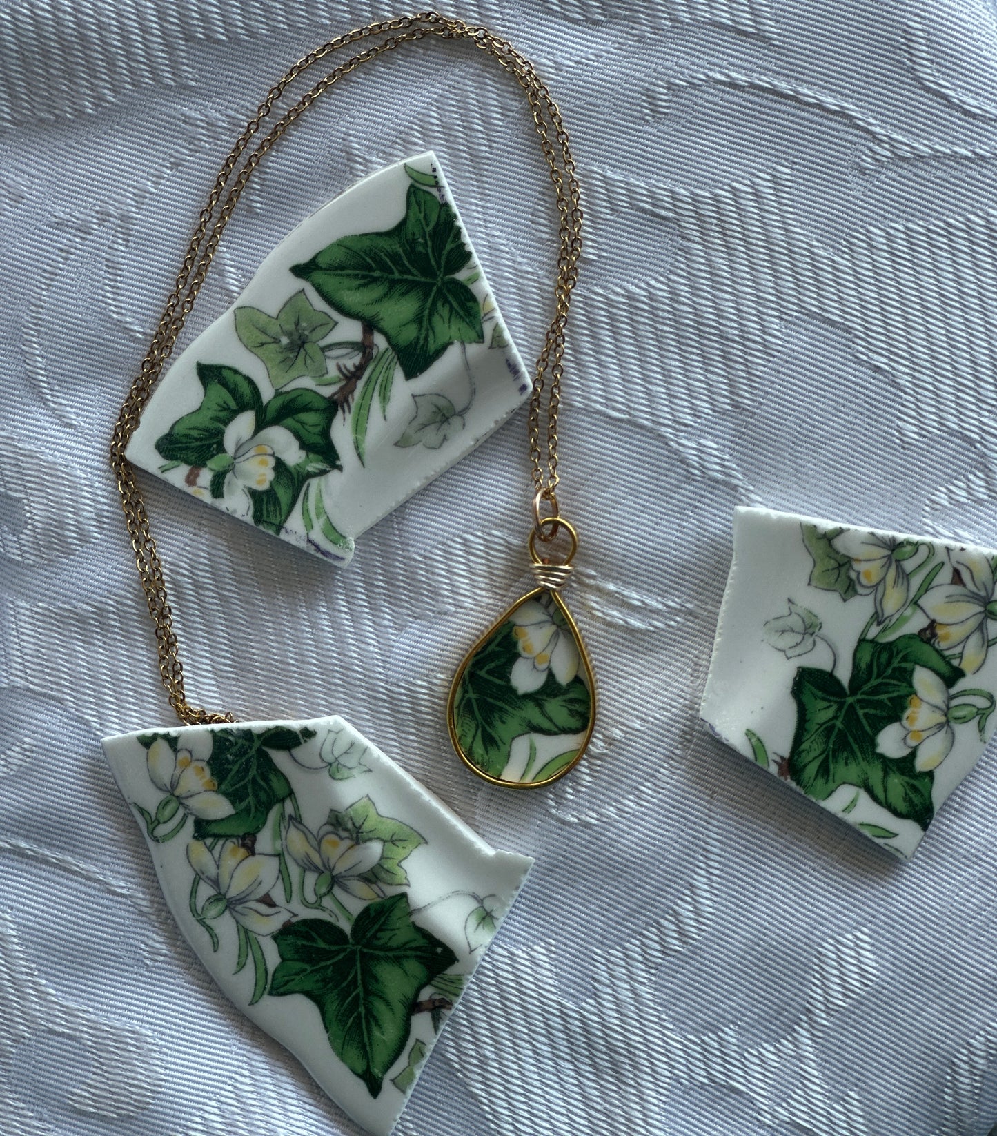 Necklace with floral pendant and matching pieces on a textured fabric background