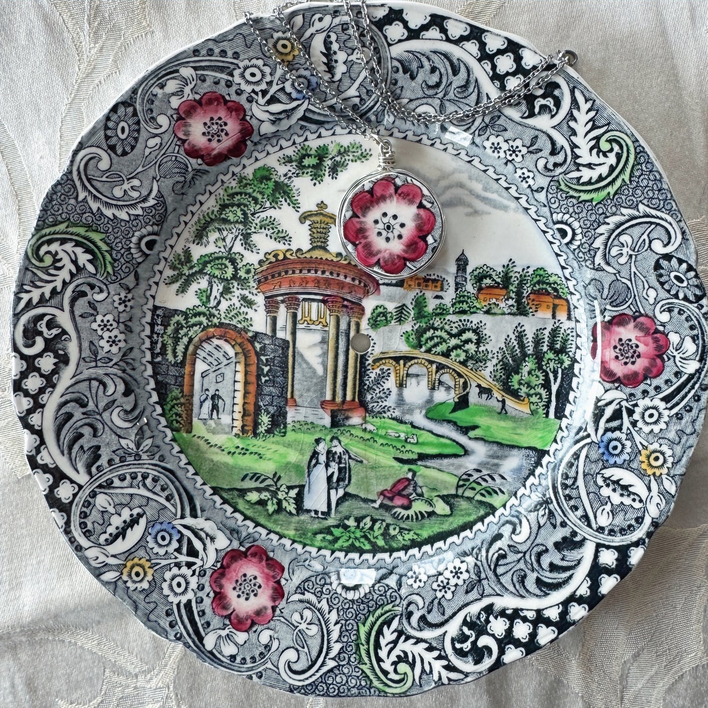 Decorative plate with intricate patterns and a scenic design on a textured fabric background
