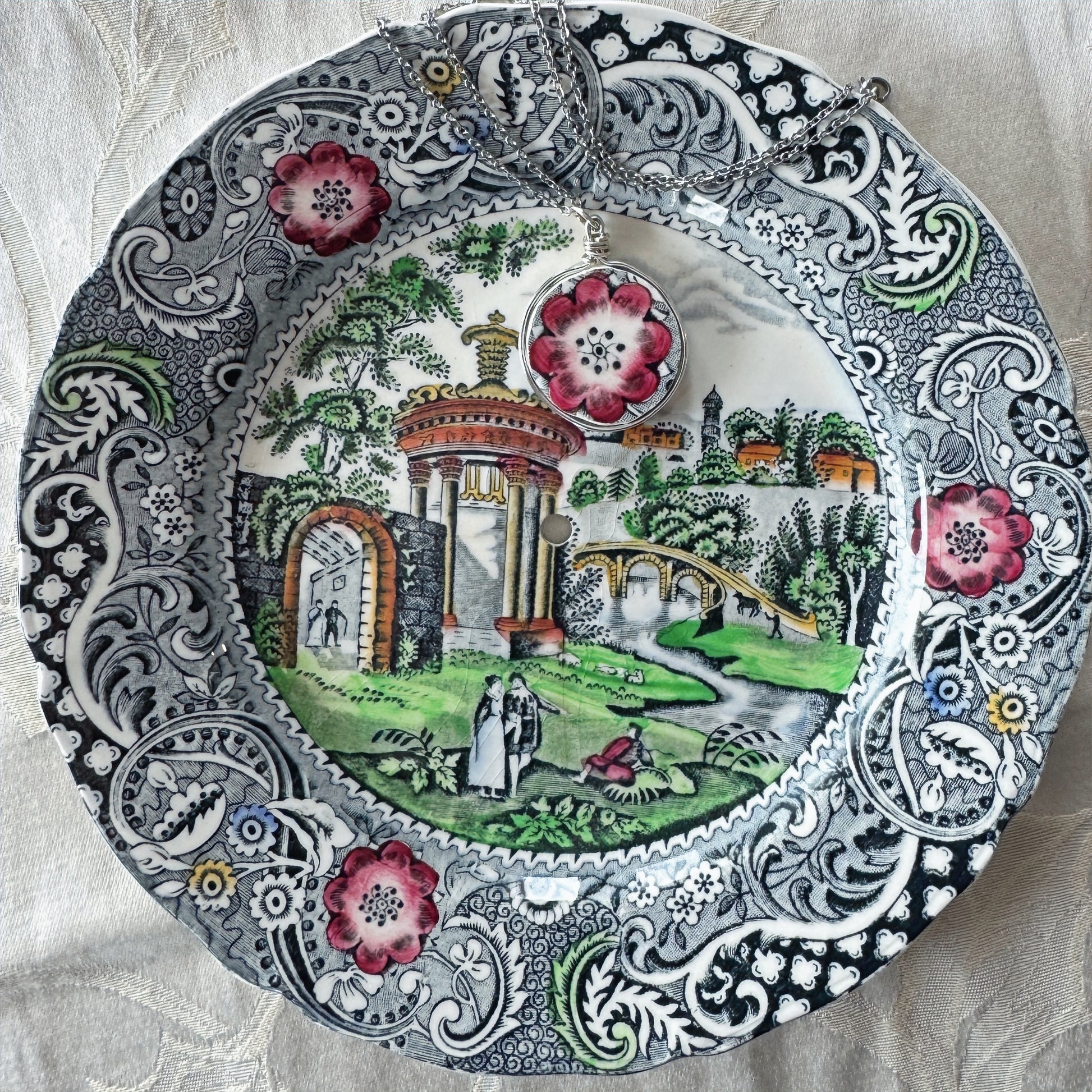 Decorative plate with intricate patterns and a scenic design on a textured fabric background