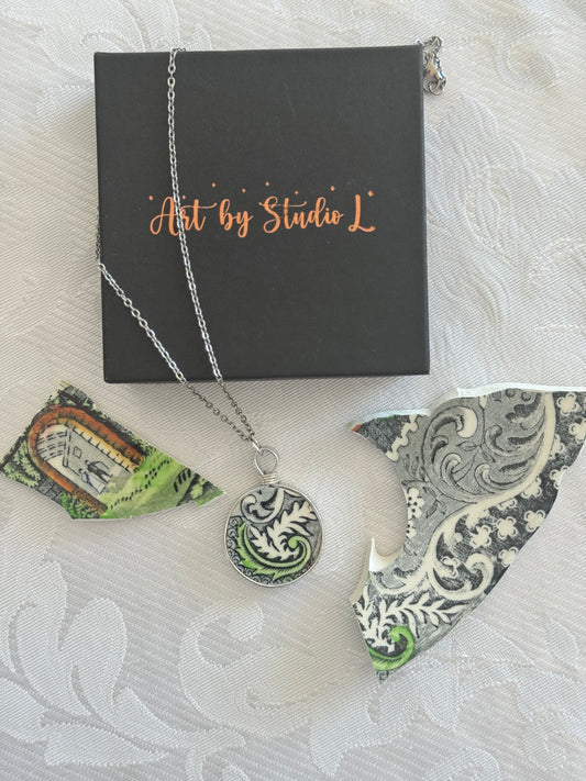 Necklace with a decorative pendant on a white textured surface with 'Art by Studio L' box.