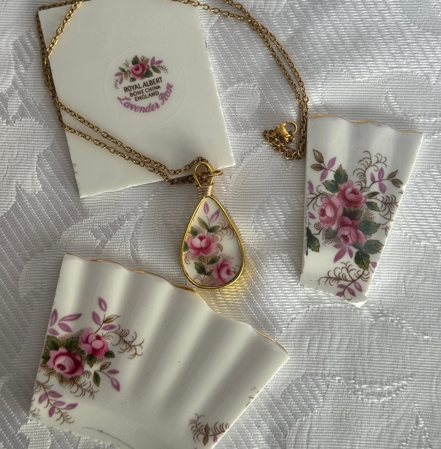 Necklace with floral pendant on a matching card and ribbon on a textured white background