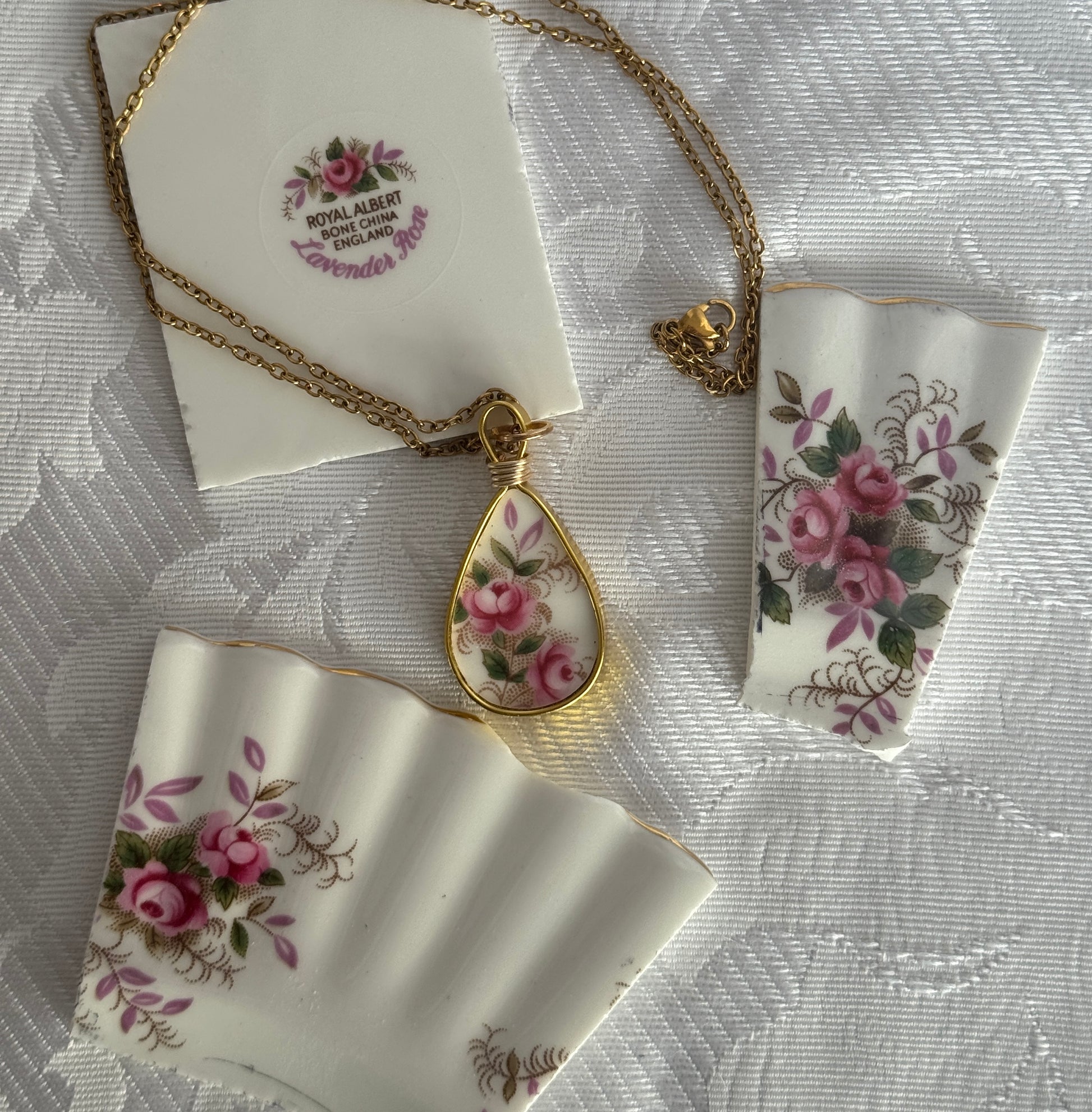 Necklace with floral pendant on a matching card and ribbon on a textured white background