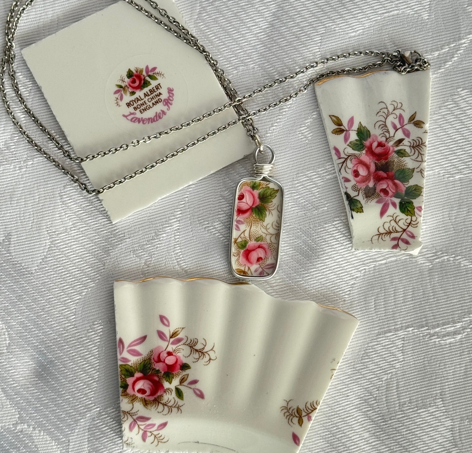 Floral pendant necklace with matching pouches on a textured surface