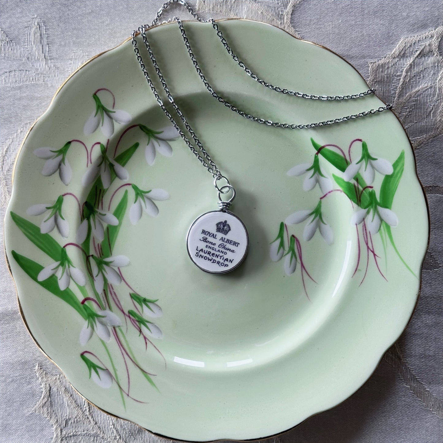 Necklace with a pendant on a decorative plate with floral design