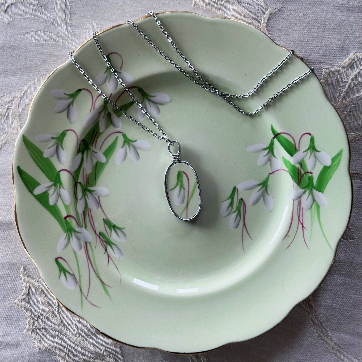 Necklace with pendant on a decorative plate with floral design