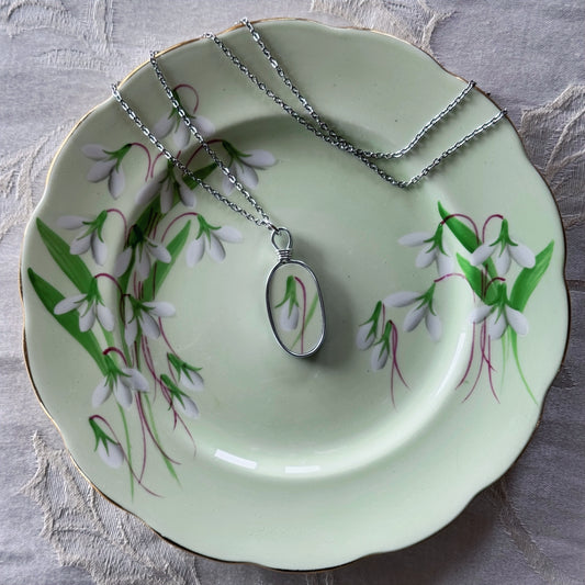 Necklace with pendant on a decorative plate with floral design