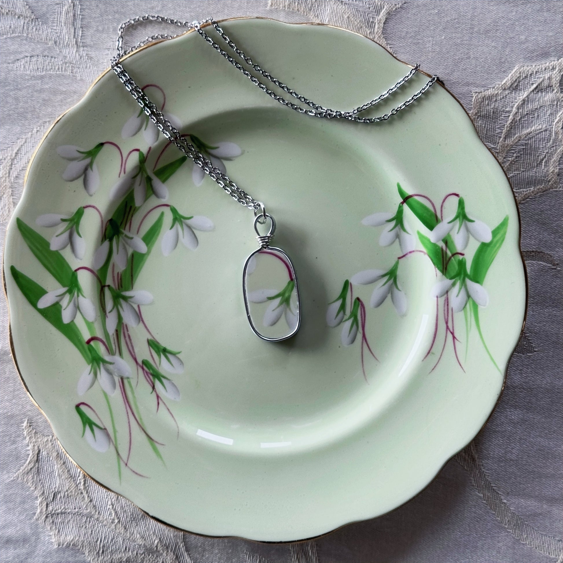 Necklace with a pendant on a decorative plate with floral design