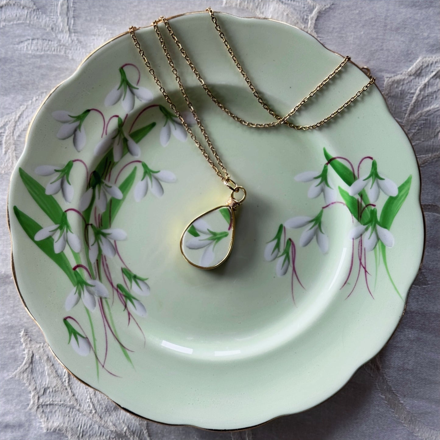 Necklace with a pendant on a decorative plate with floral design