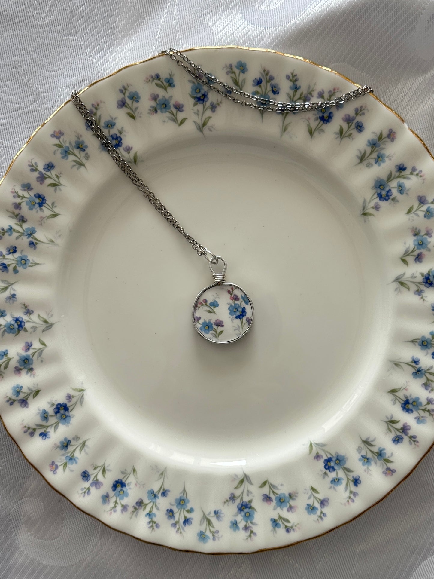 Necklace with a floral pendant on a decorative plate with floral patterns