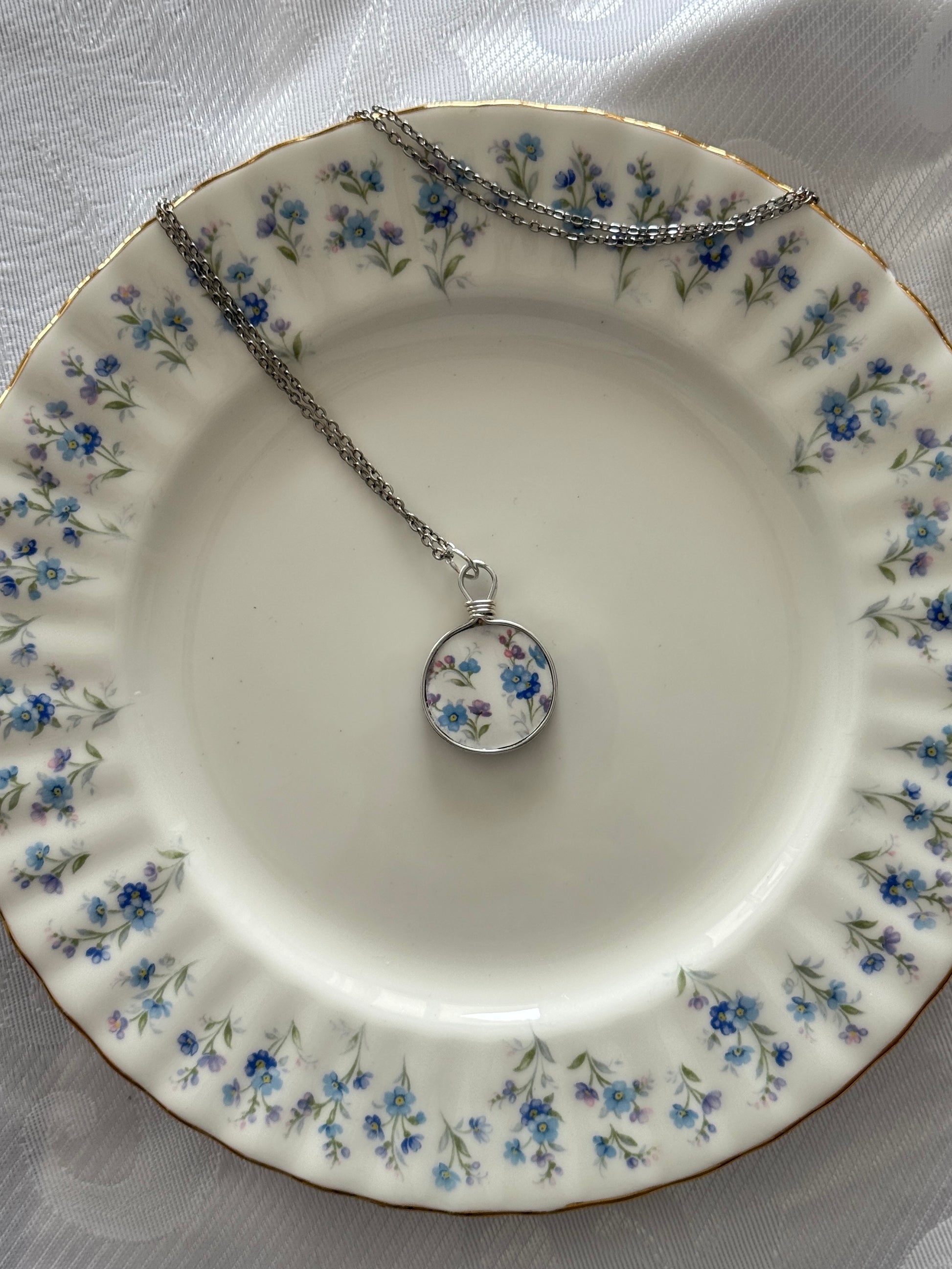 Necklace with a floral pendant on a decorative plate with floral patterns