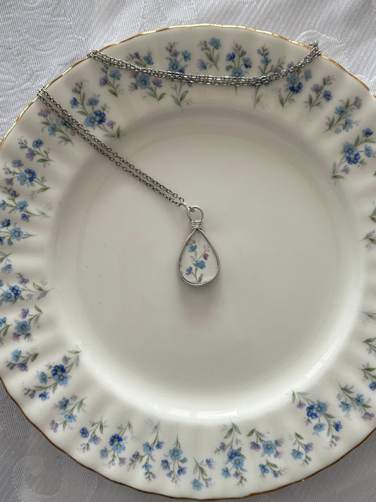 Necklace with a teardrop pendant on a decorative plate with floral pattern