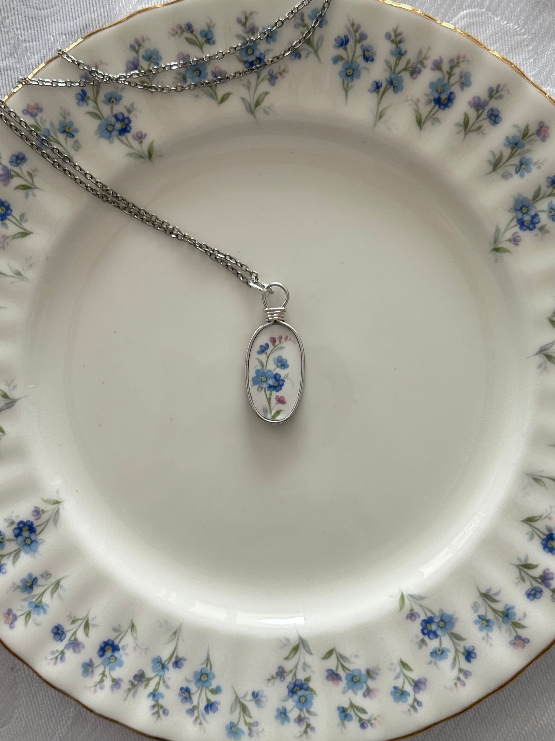 Necklace with a floral pendant on a decorative plate with floral patterns