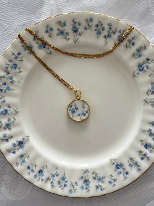 Necklace with a floral pendant on a decorative plate with floral patterns