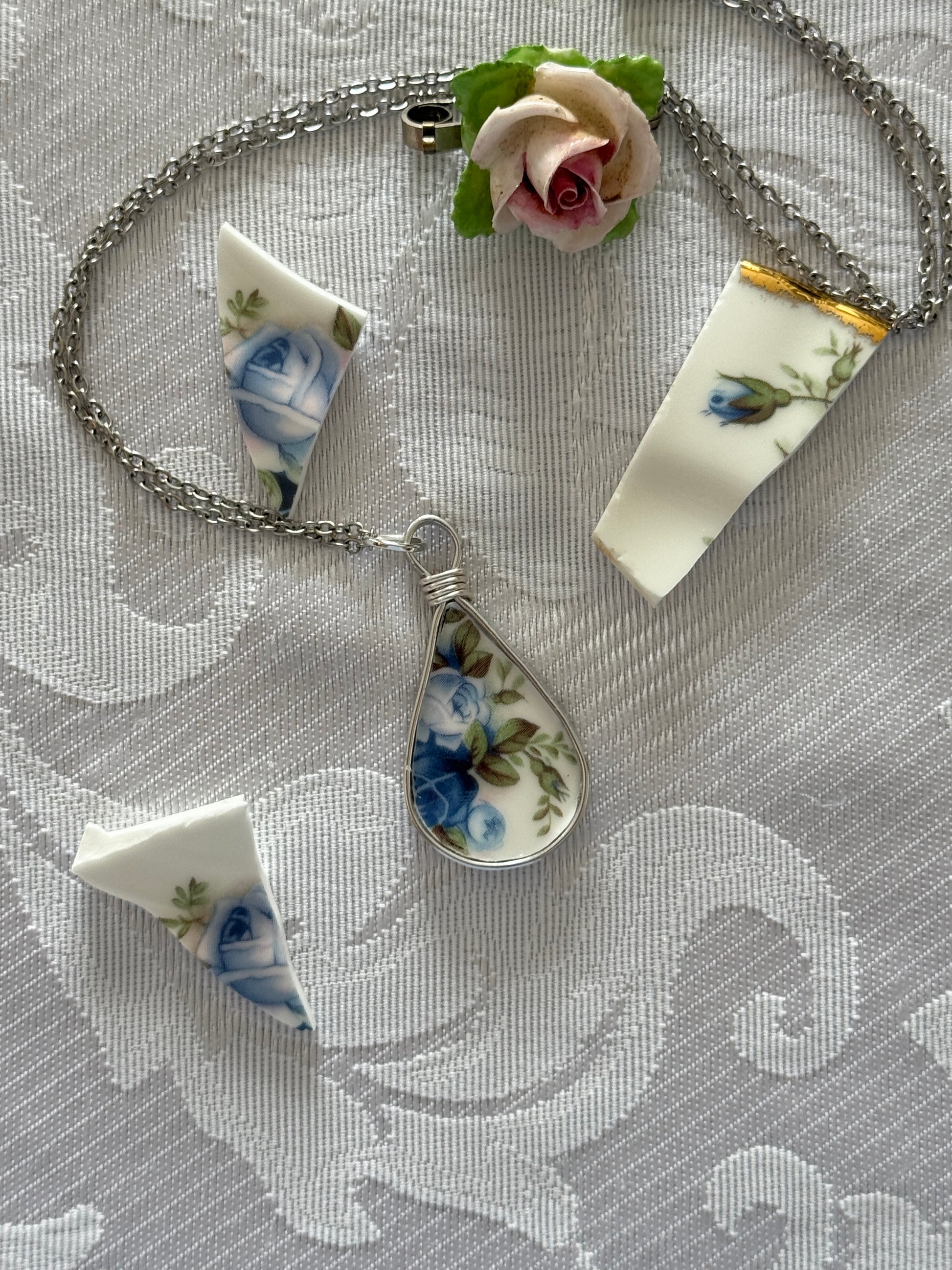 Necklace with a teardrop-shaped pendant featuring floral patterns on a textured surface.