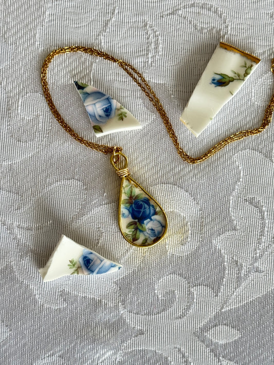Necklace with a teardrop-shaped pendant featuring floral design on a textured fabric background