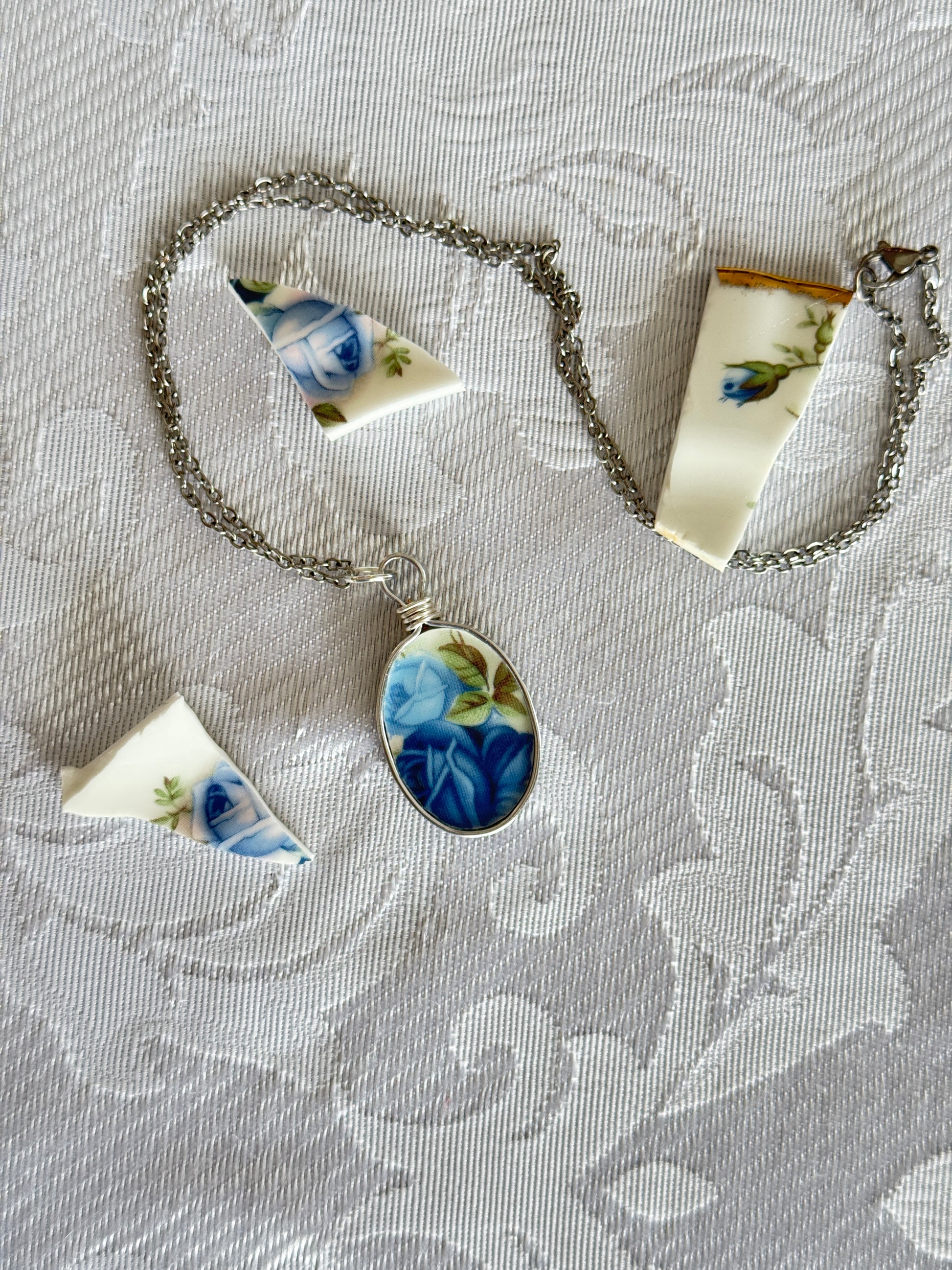 Necklace with floral pendant and matching pieces on a textured surface