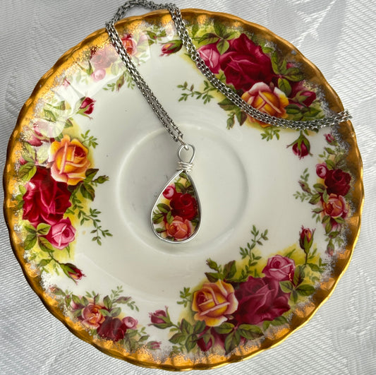 Teardrop-shaped pendant with floral design on a decorative plate with rose pattern