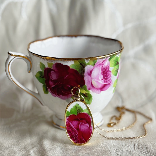 Teacup with floral design and matching pendant on a white fabric background