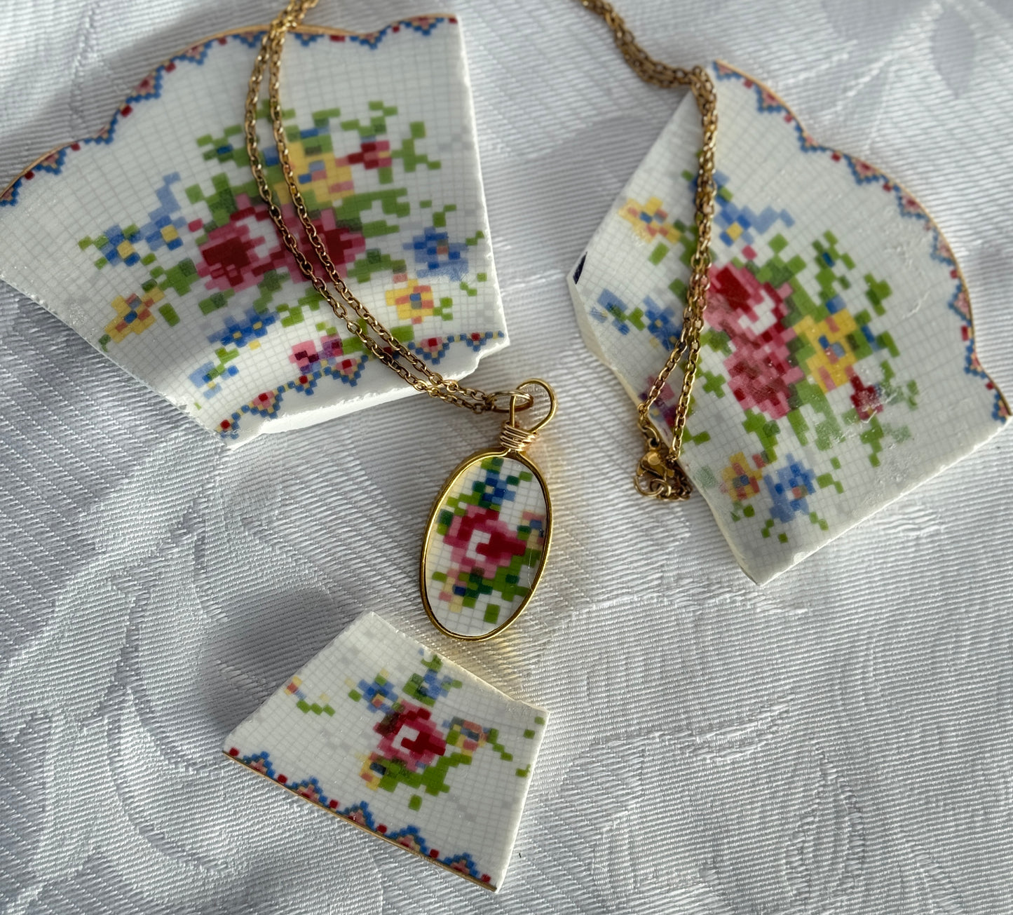 Gold necklace with floral pendant on a textured white surface