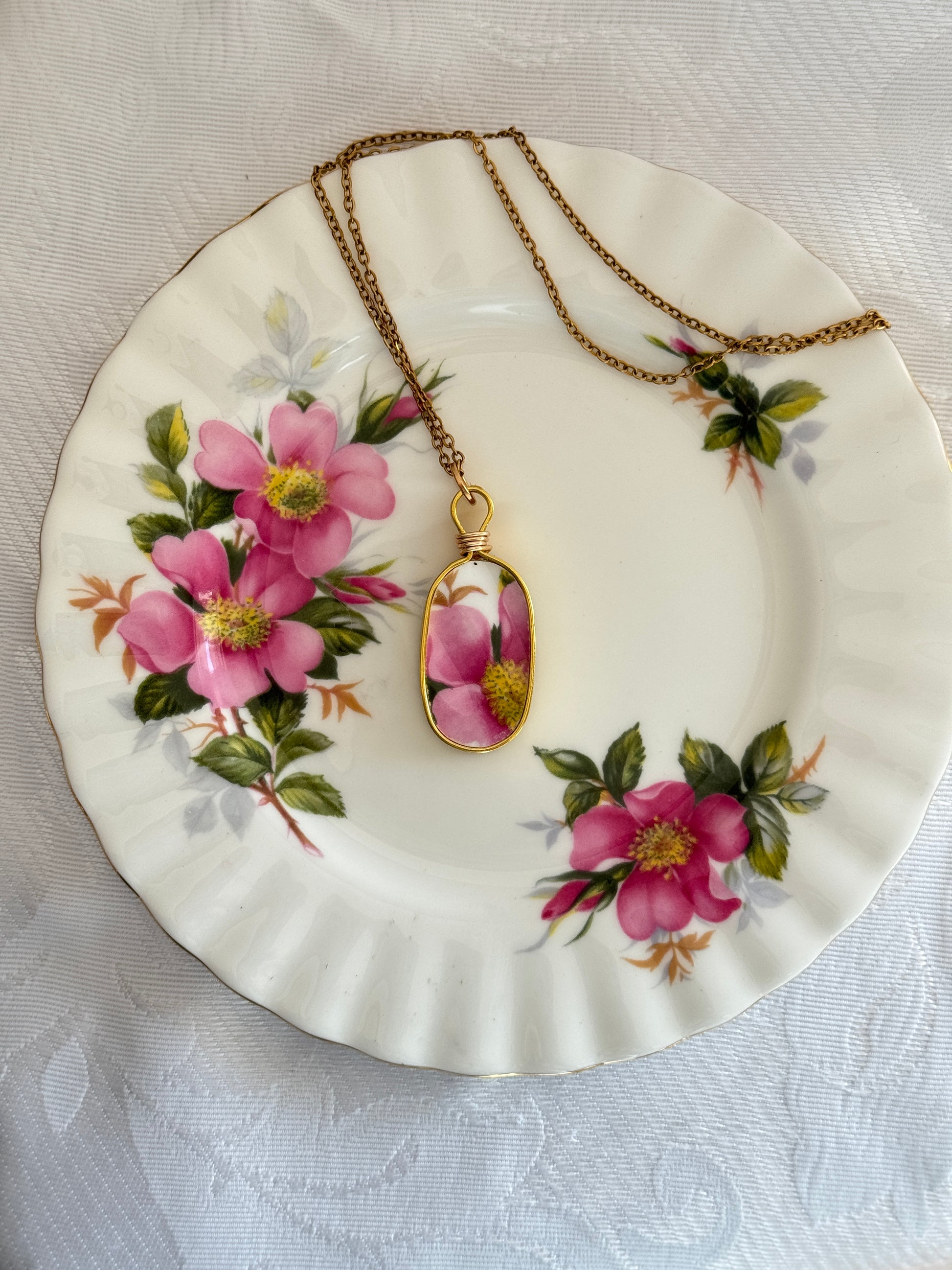 Necklace with a floral pendant on a decorative plate with pink flowers