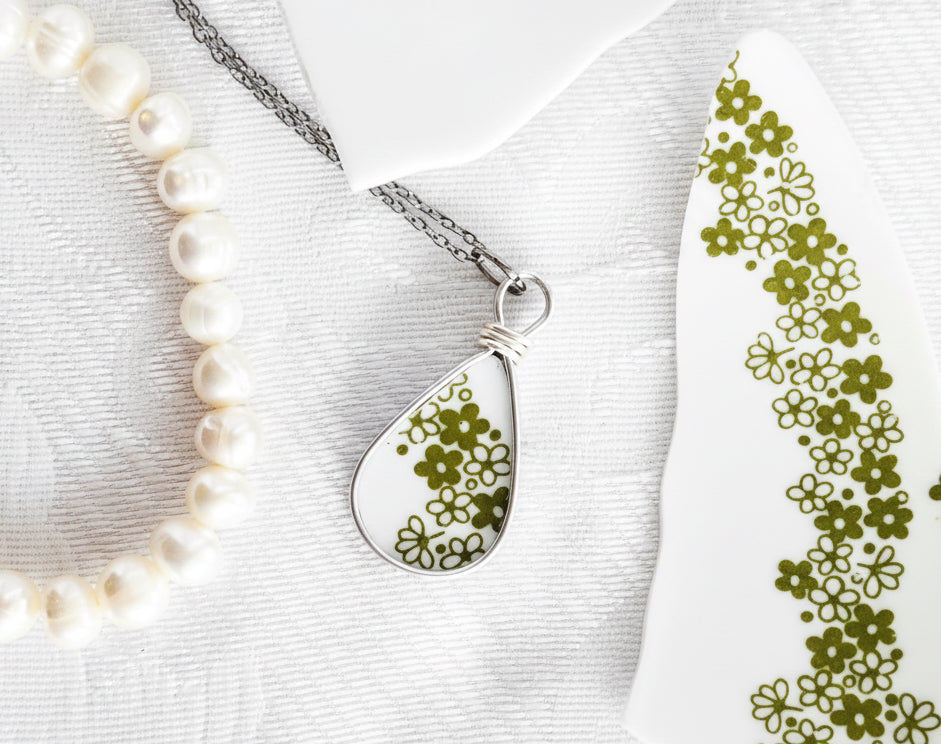 Teardrop-shaped pendant with floral design on a white background