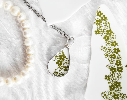 Teardrop-shaped pendant with floral design on a white background