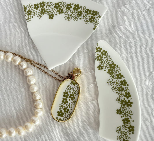 Pearl necklace with a floral pendant on a textured surface