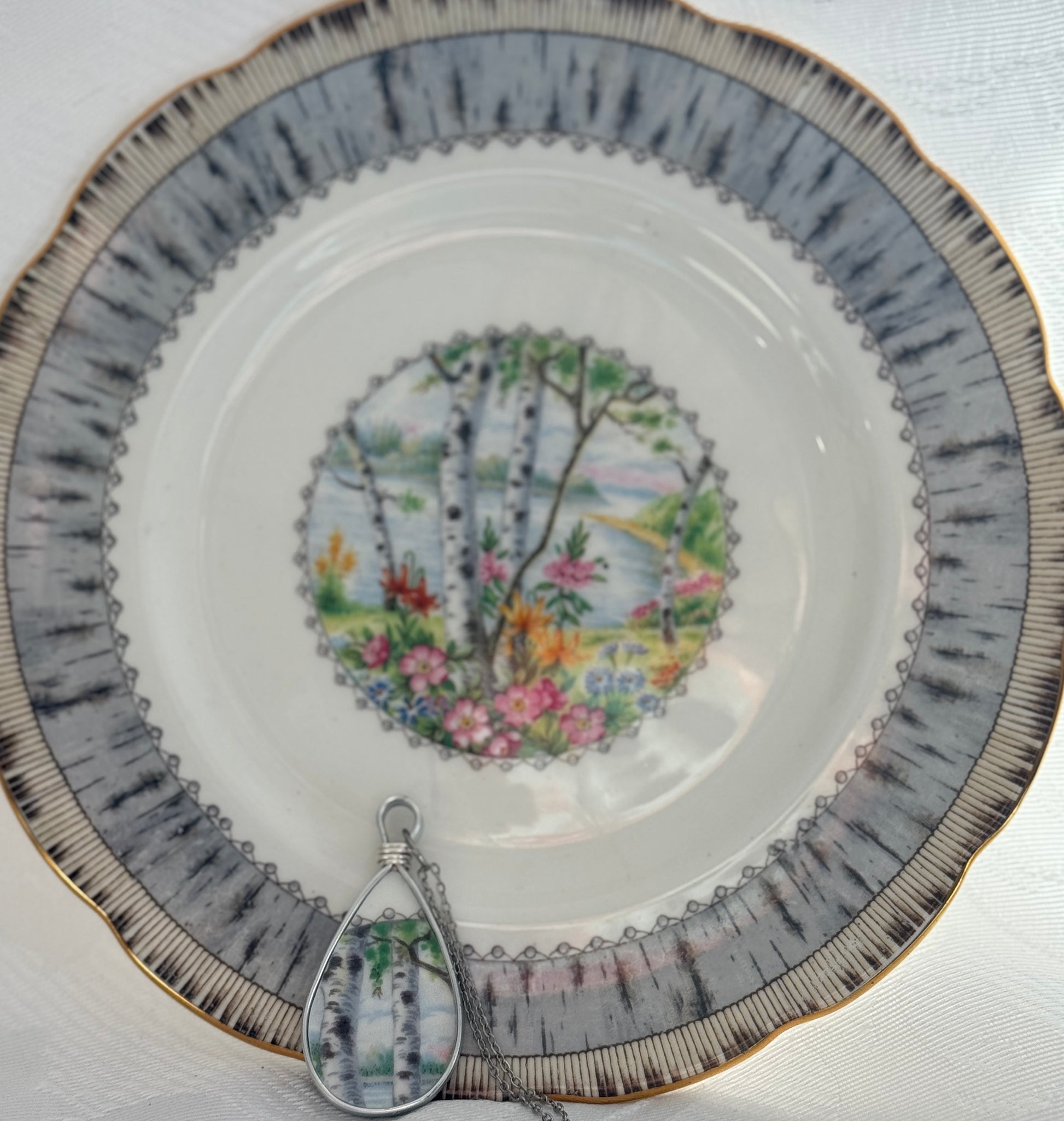 Decorative plate with floral design and a teardrop-shaped pendant on a white background