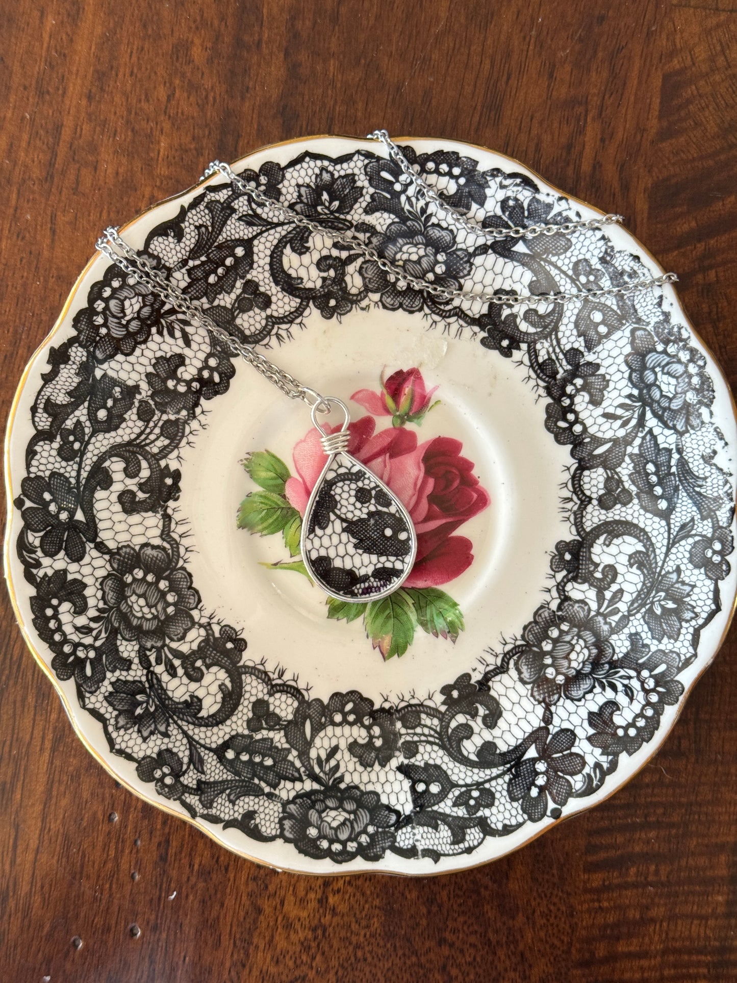 Decorative plate with black lace and floral design on a wooden surface