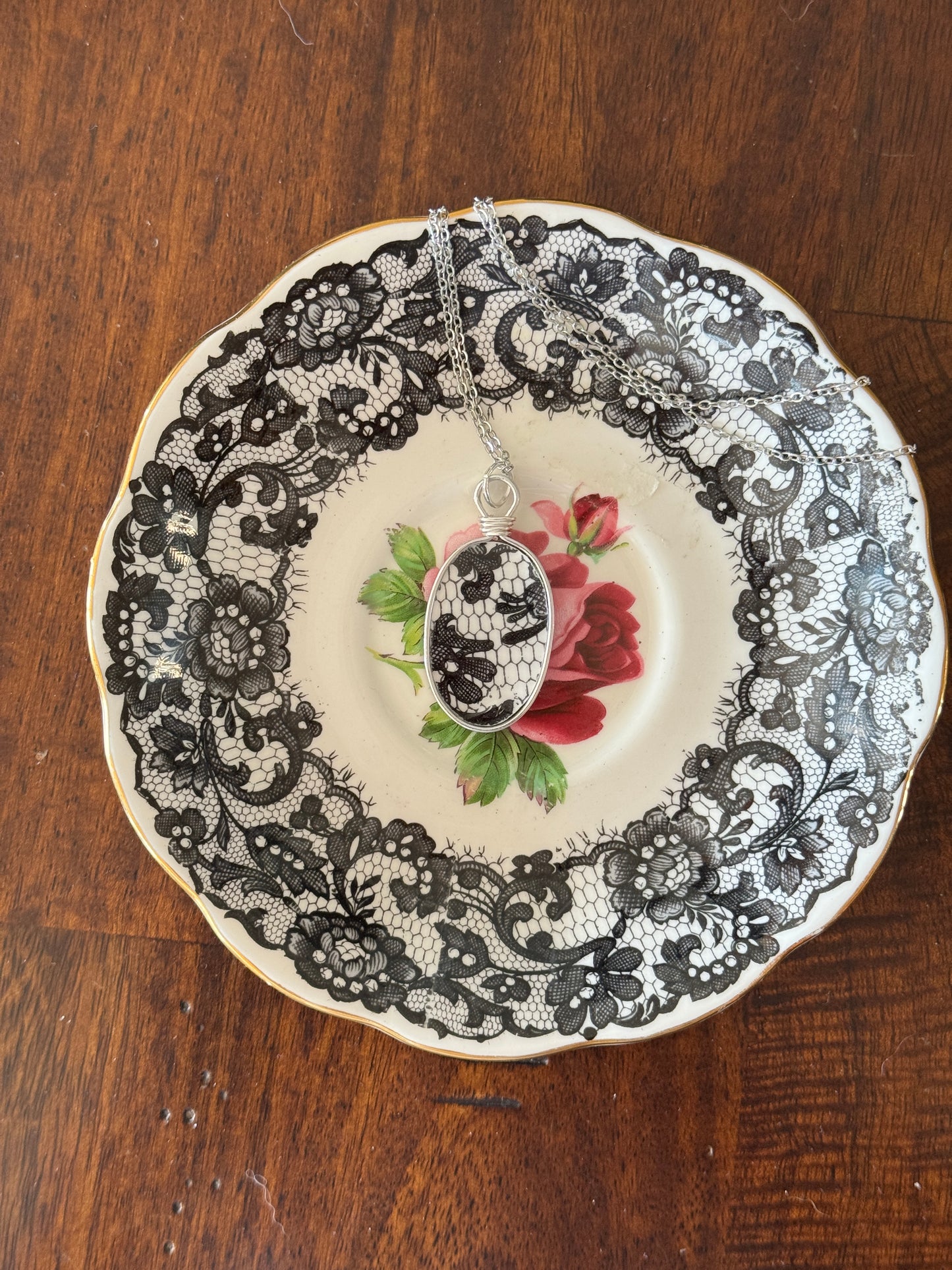 Decorative plate with black lace around a central floral design on a wooden surface